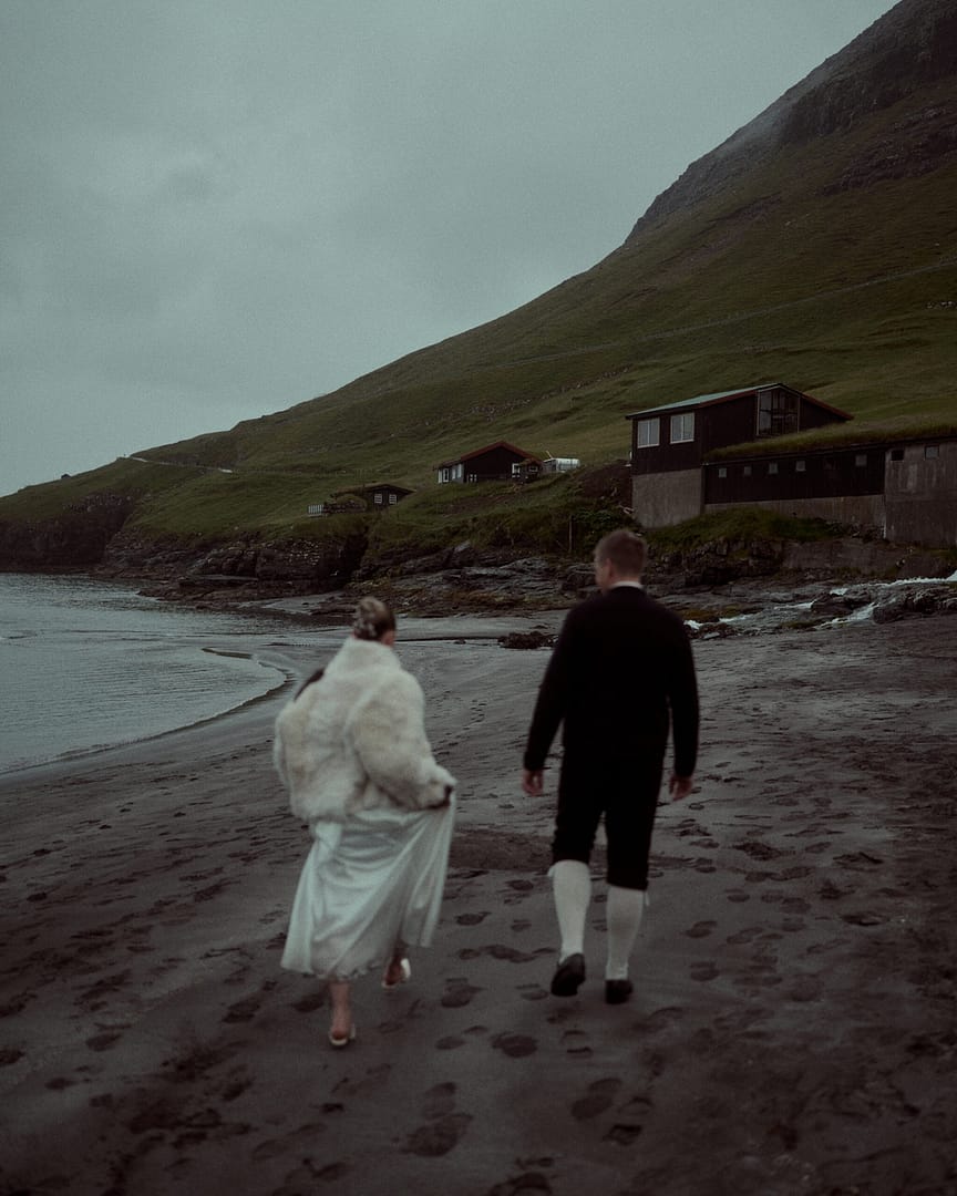 wedding couple running on the sand in the village bøur faroe islands